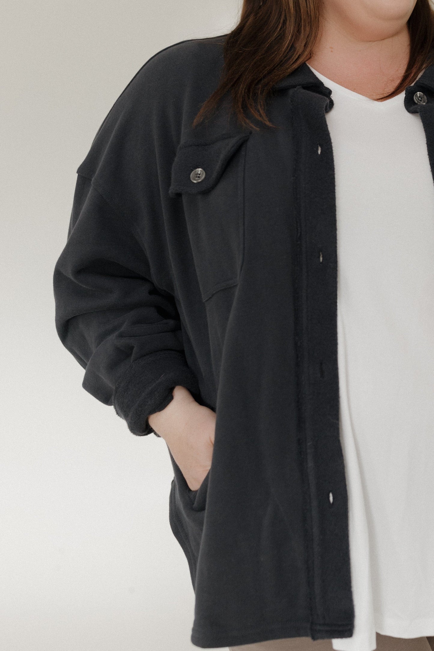 Person wearing a black jacket over a white shirt on a plain background