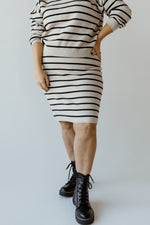 Person wearing a knee-length knit striped pencil skirt with a ribbed waistband and black boots, standing on a light background.