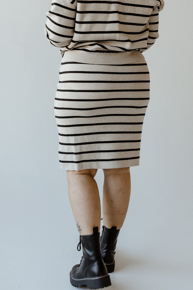 Person wearing a knee-length knit striped pencil skirt with a ribbed waistband and black boots, standing on a light background.