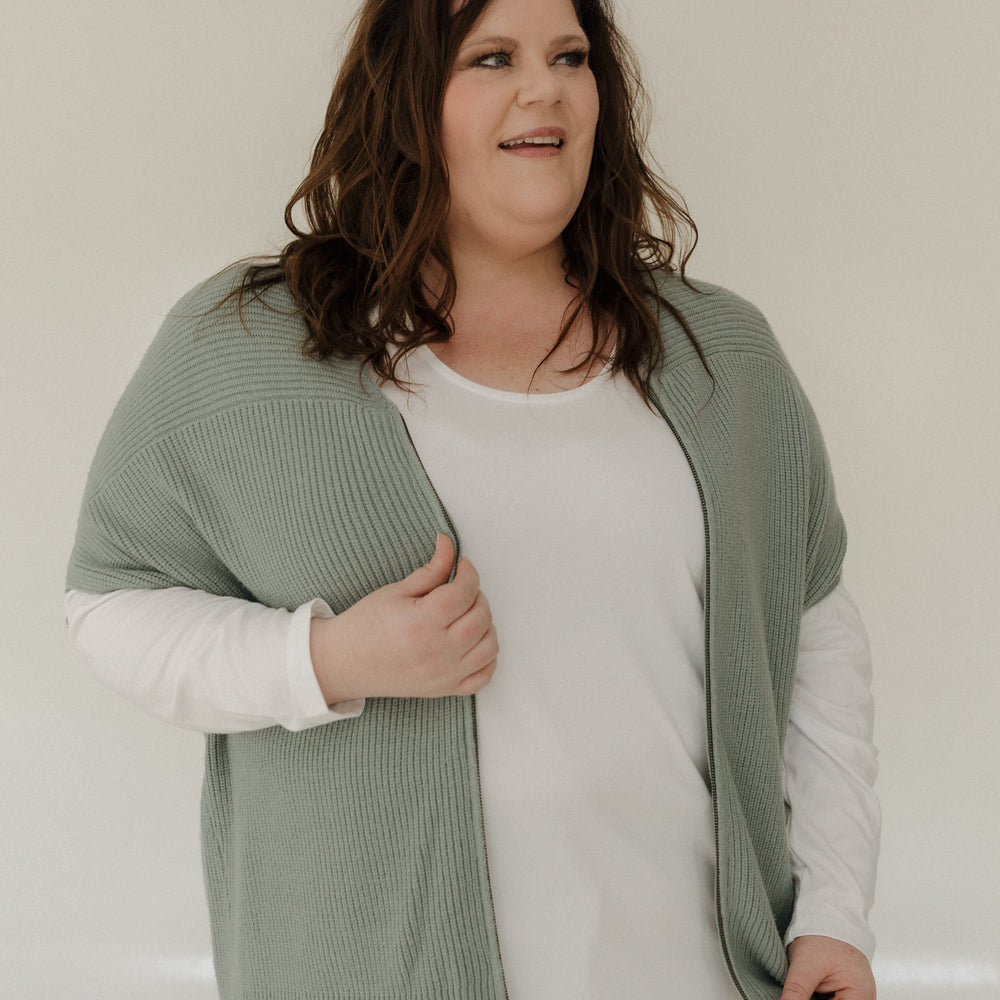 Woman wearing a green cardigan over a white shirt with a neutral background
