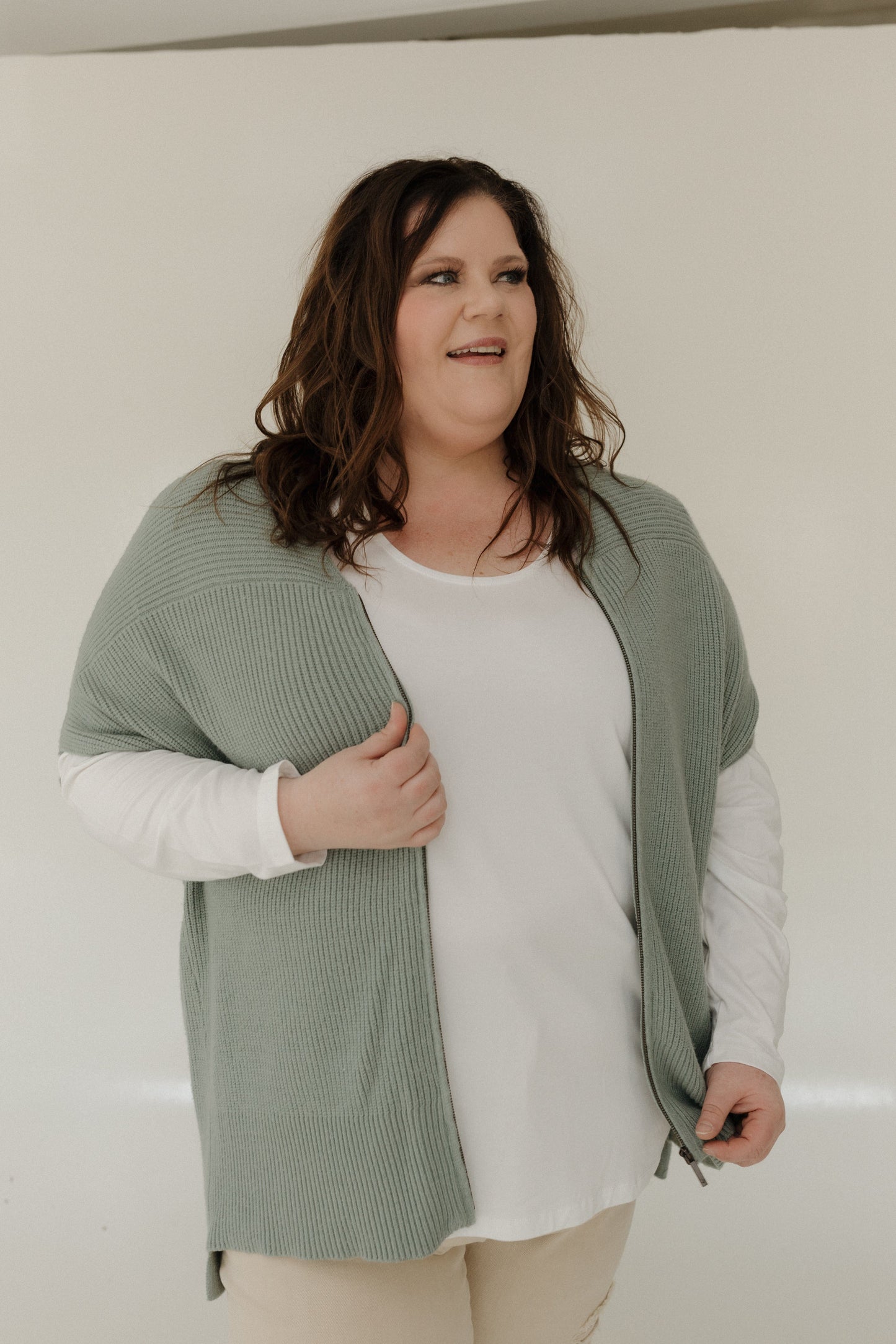 Woman wearing a green cardigan over a white shirt with a neutral background