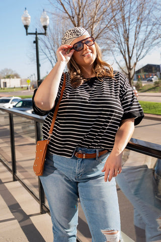 Woman wearing a striped shirt, jeans, and sunglasses on a sunny day.