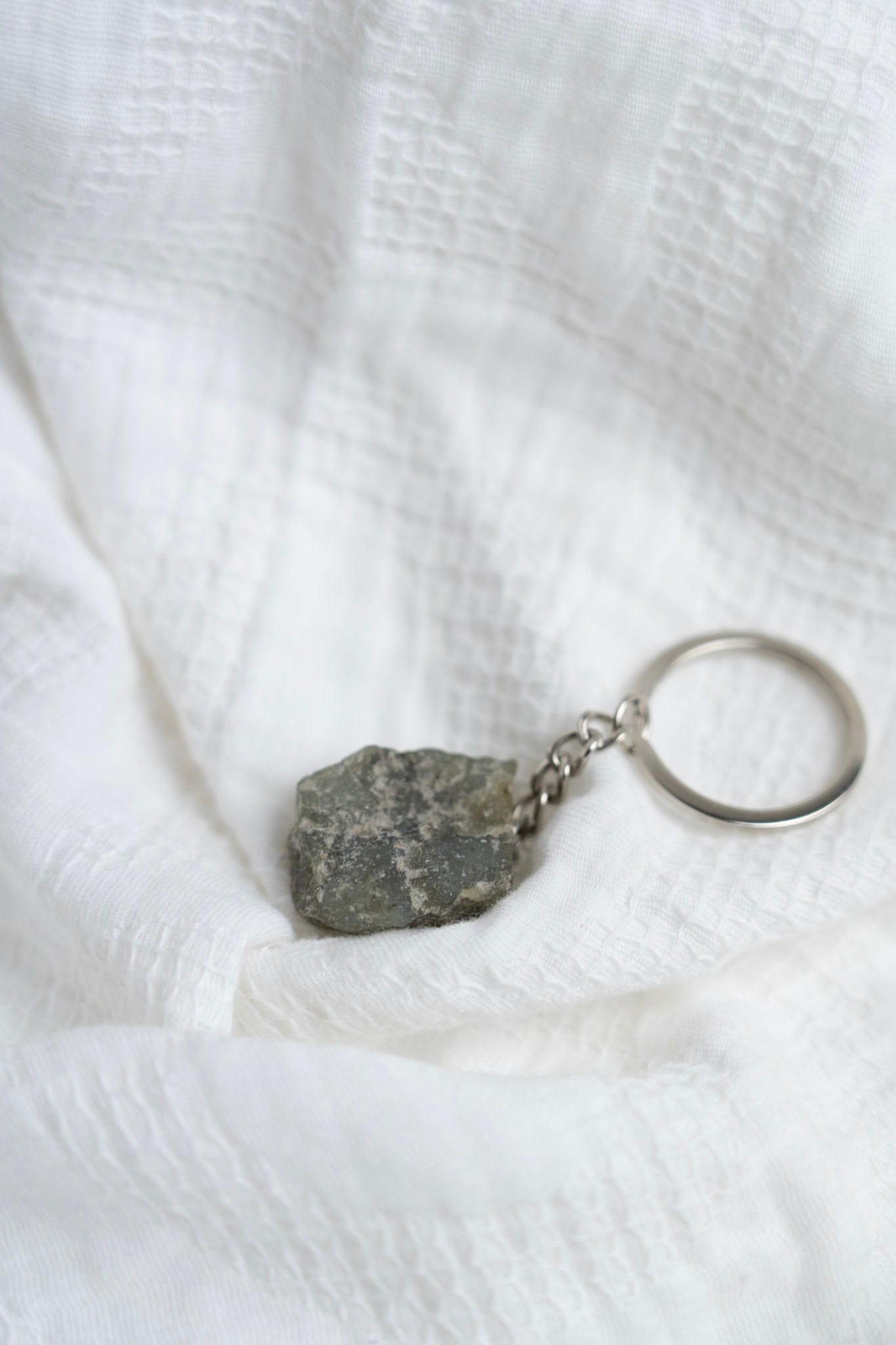 Keychain with a Labradorite charm on a white textured fabric background