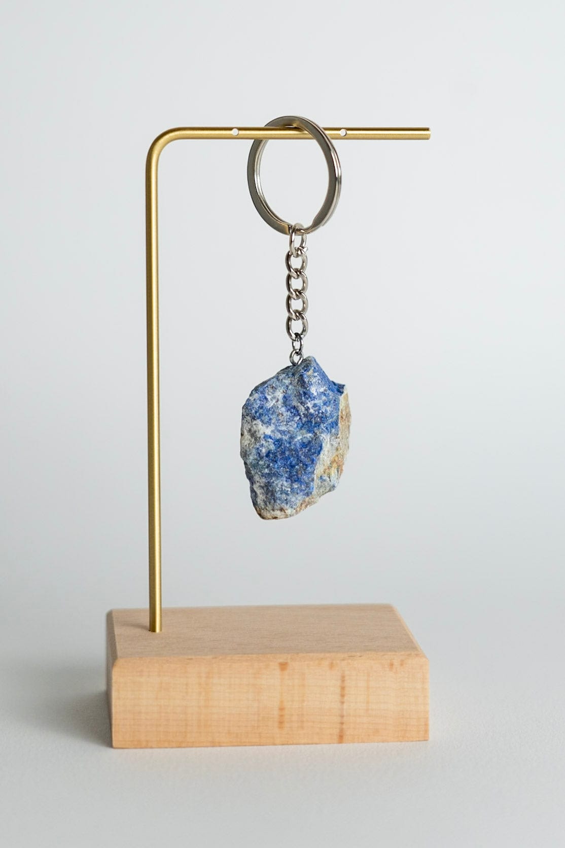 Keychain with a blue stone on a wooden stand against a light gray background