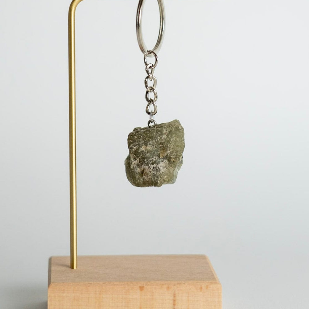Keychain with a stone on a wooden block and brass stand against a light gray background