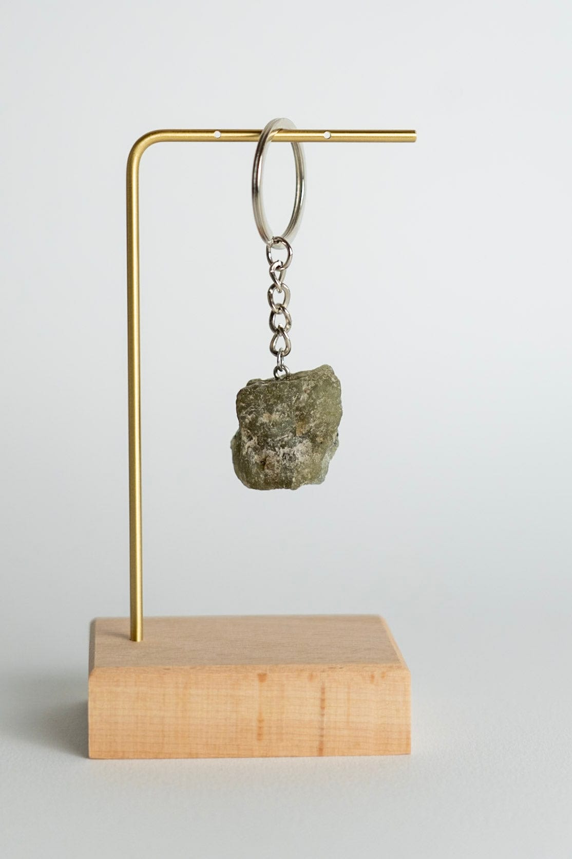 Keychain with a stone on a wooden block and brass stand against a light gray background