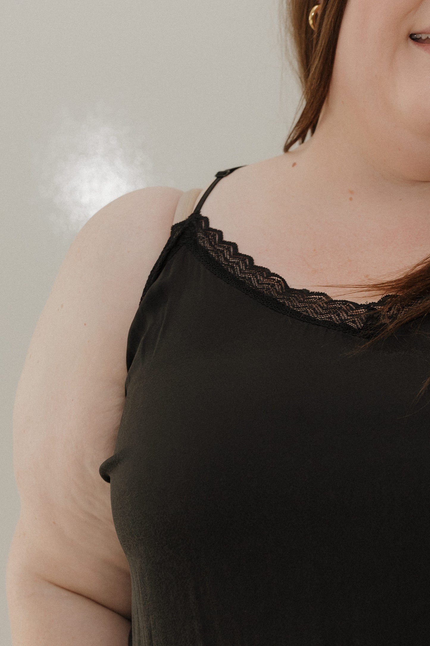 Black tank top with lace trim worn by a person against a neutral background