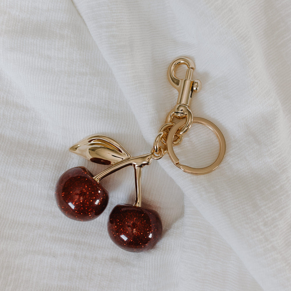Gold keychain with cherries on a white fabric background