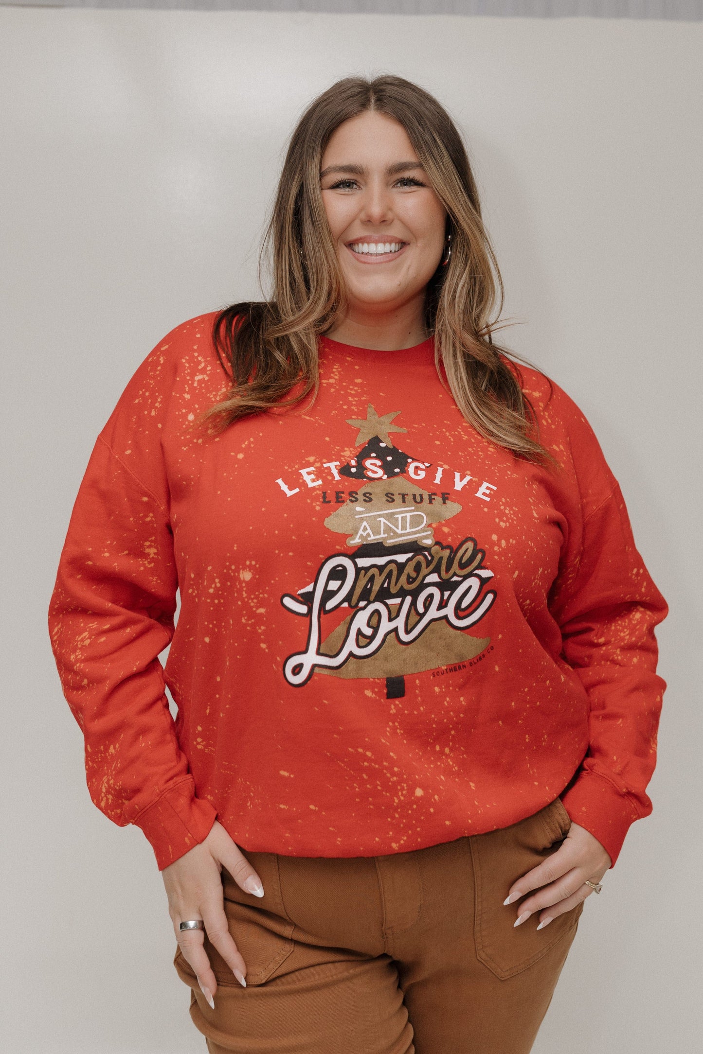 Woman wearing a red sweatshirt with a graphic design and text, standing against a plain background.