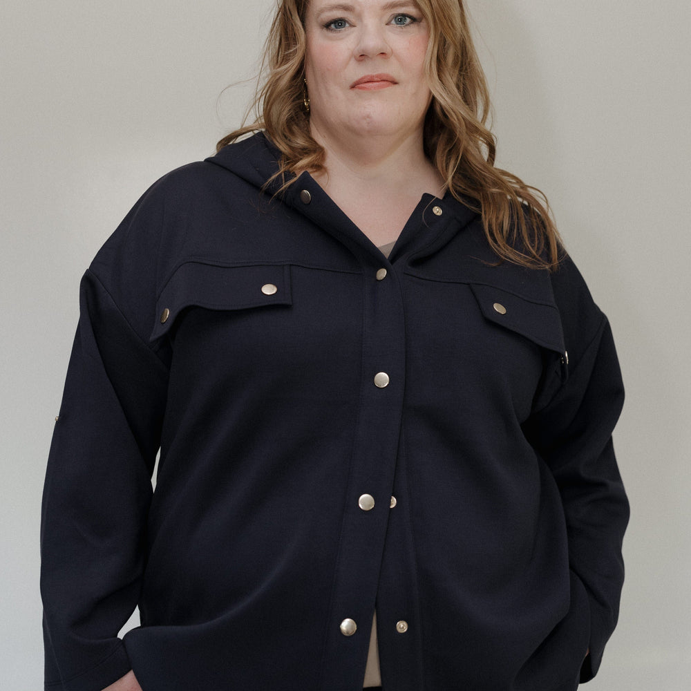 Person wearing a dark blue jacket with button details against a plain background