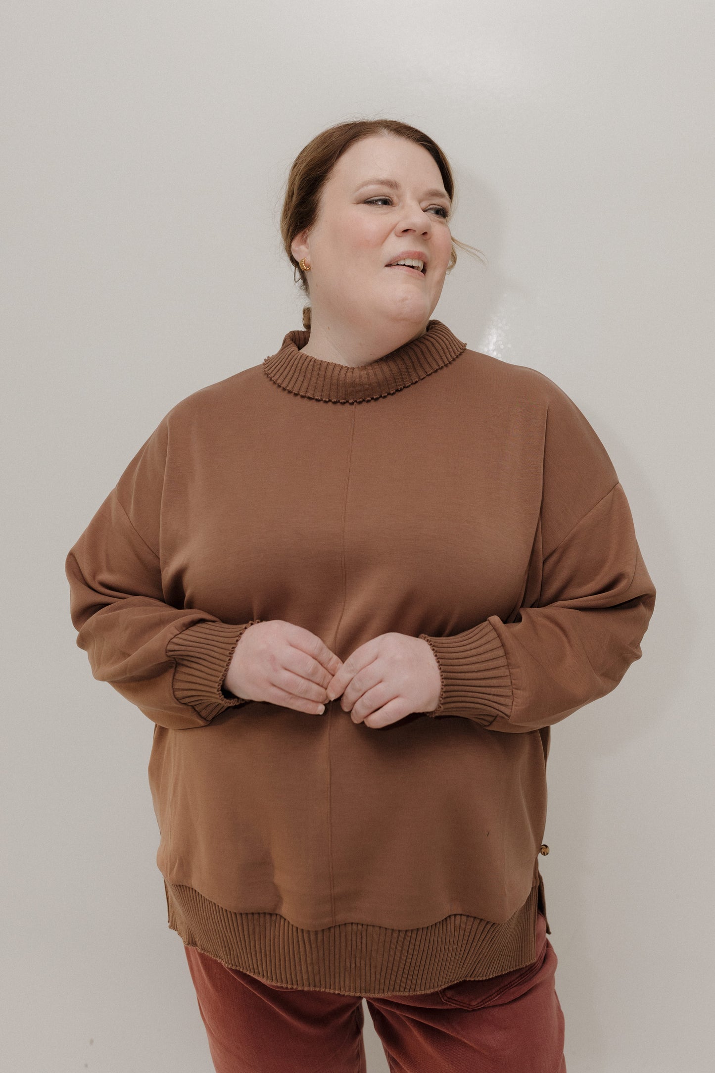 Person wearing a brown sweater against a plain background