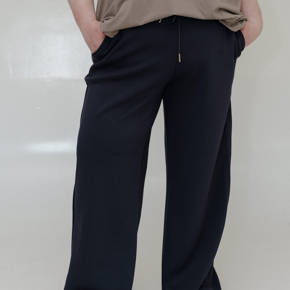 Person wearing a brown shirt and navy pants on a white background