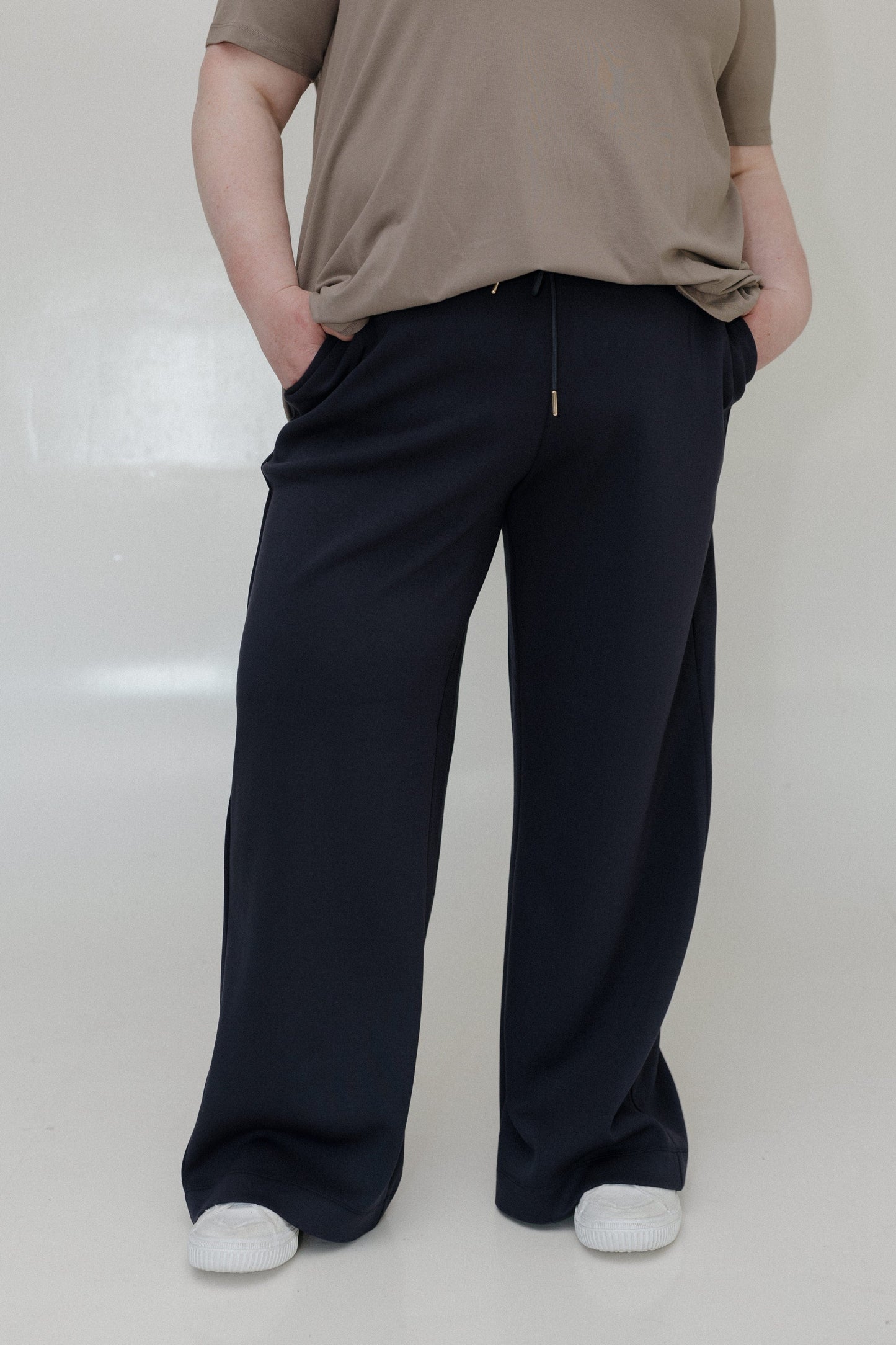 Person wearing a brown shirt and navy pants on a white background