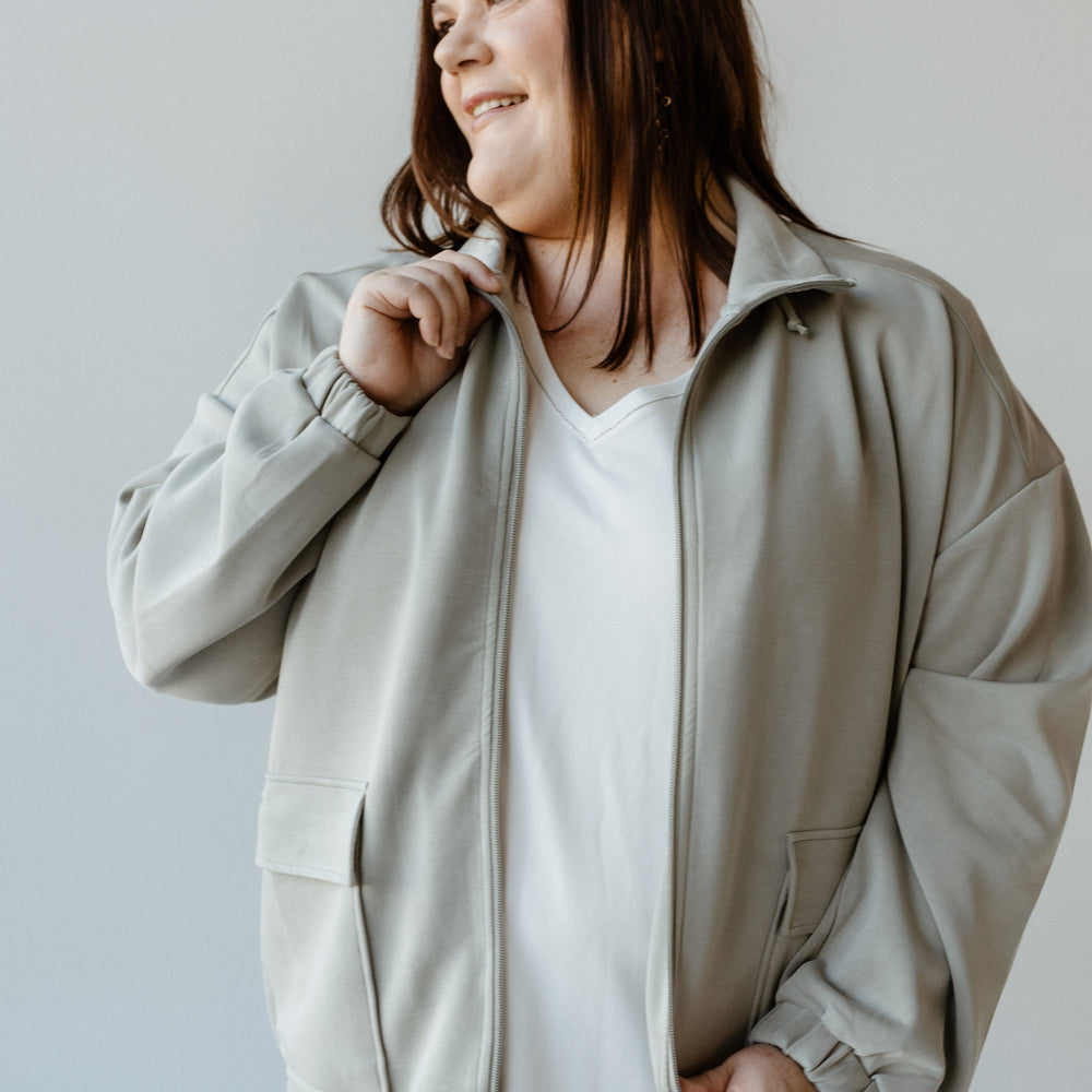 A person wearing a stylish urbanite jacket and white shirt smiles while looking to the side.