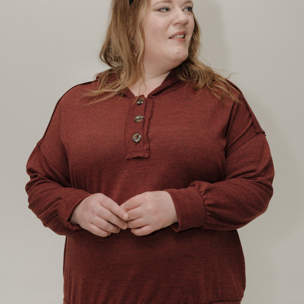 Person wearing a wine sweater against a plain background