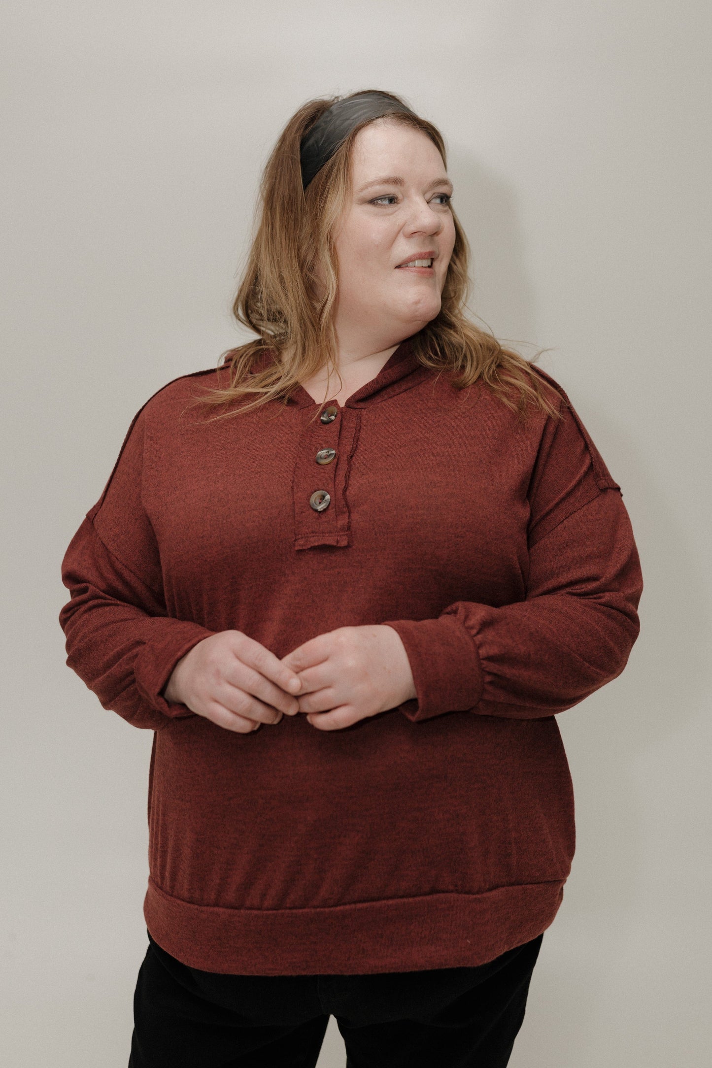 Person wearing a wine sweater against a plain background