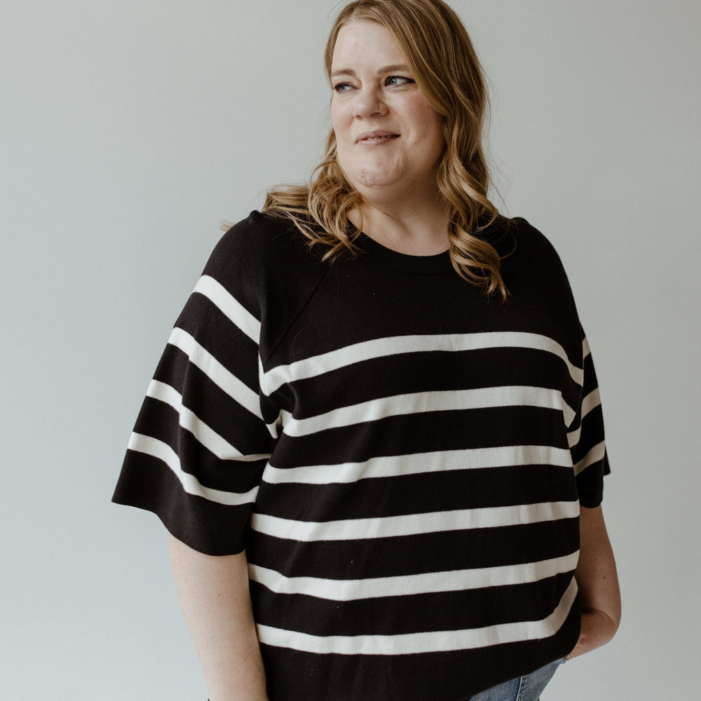 A woman in Yesta's Lightweight Stripe Sweater in Black and Ecru, featuring ultra flattering stripes and an elegant round neckline.