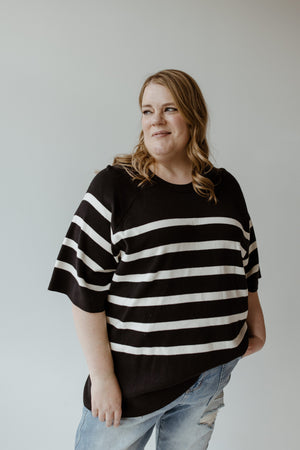 A woman in Yesta's Lightweight Stripe Sweater in Black and Ecru, featuring ultra flattering stripes and an elegant round neckline.