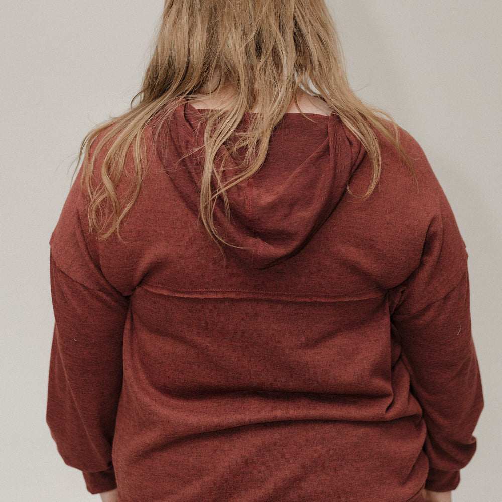 Person wearing a red hoodie from behind on a plain background