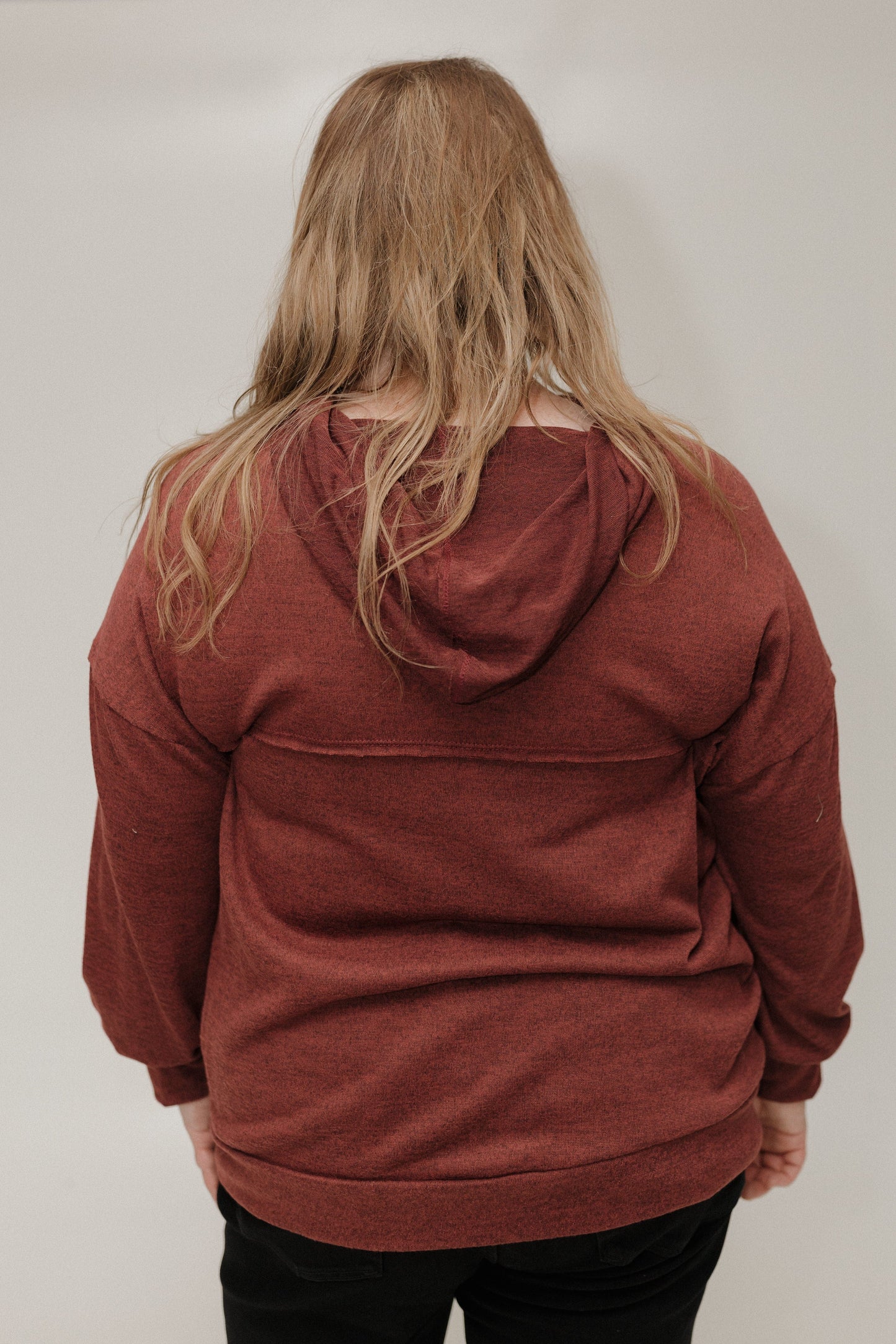 Person wearing a red hoodie from behind on a plain background