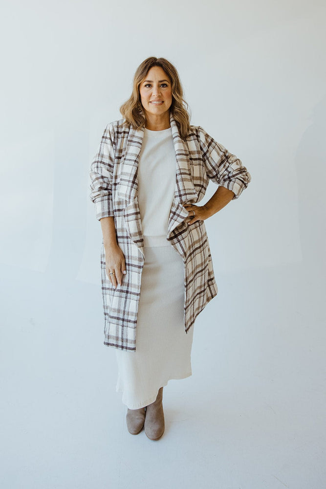 A person wearing the Andrea by Unit LIGHTWEIGHT PLAID MIDI BLAZER over a white outfit is shown adjusting the collar, displaying a ring on their finger.