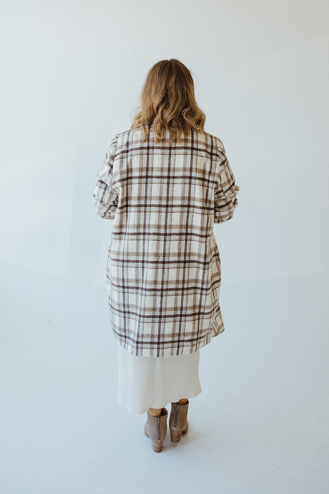 Back view of a person with long hair wearing an Andrea by Unit LIGHTWEIGHT PLAID MIDI BLAZER, white skirt, and beige boots, standing against a plain light background.