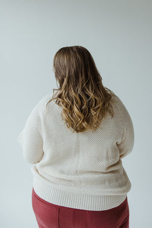 A person with long wavy hair, wearing the Yesta Lightweight Raglan Sleeve Turtleneck in Snowy White and red pants, is standing with their back to the camera.