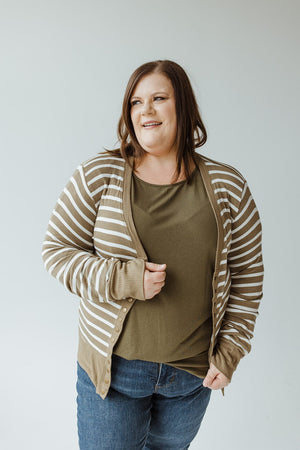 A woman with shoulder-length hair smiles while wearing a green top, blue jeans, and the Zenana Lightweight Striped Snap Cardigan in khaki and ivory. She is standing against a plain light background.