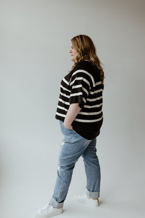 A woman in a Yesta lightweight stripe sweater in black and ecru showcases the elegant round neckline of her ultra-flattering design.