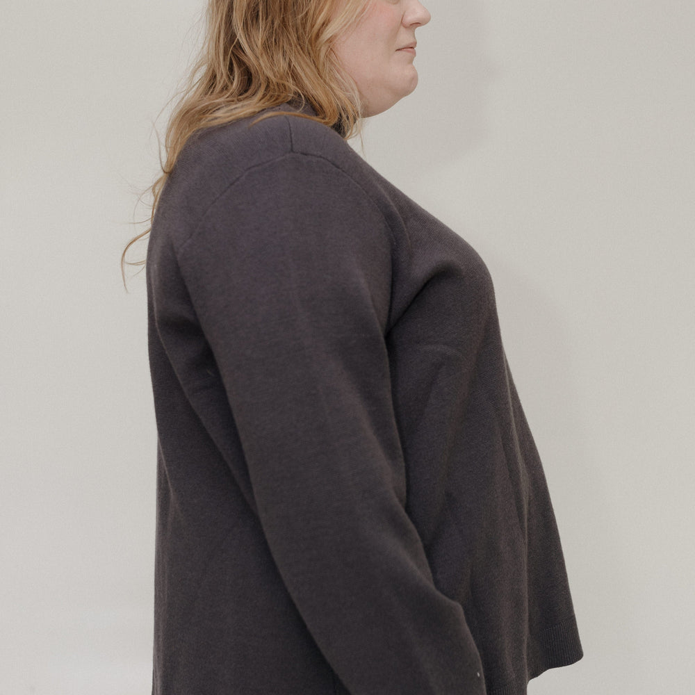 Person wearing a dark gray sweater against a plain background