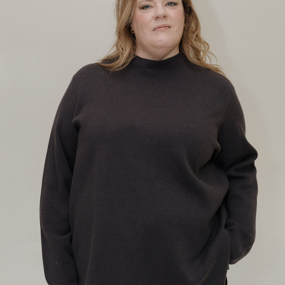 Person wearing a black sweater against a plain background