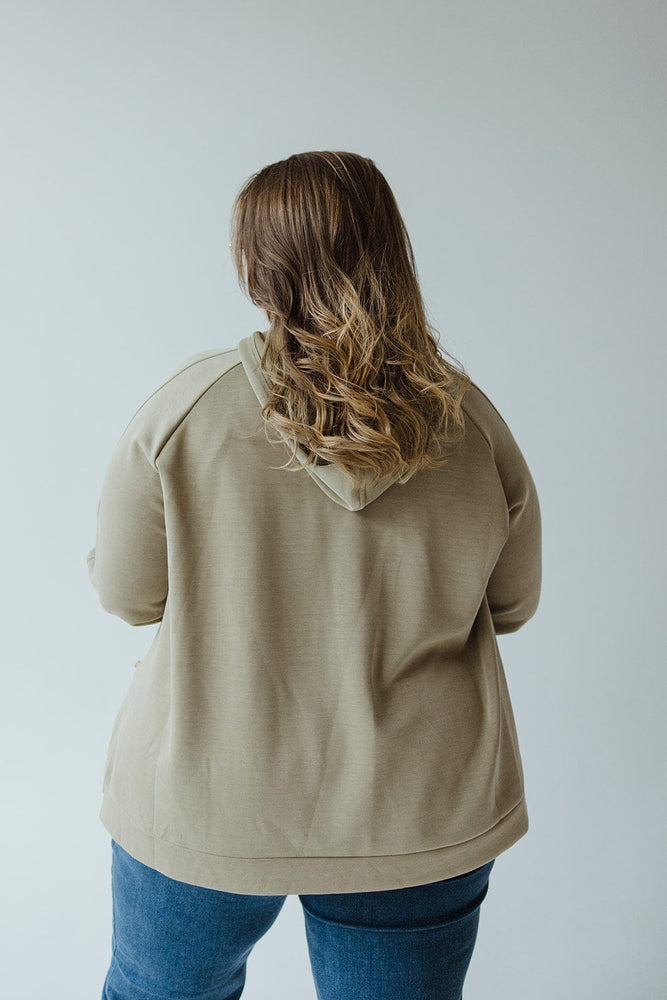 A person with long hair, wearing a green Light as Air Double-String Hoodie by Yesta and blue jeans, is photographed from the back.