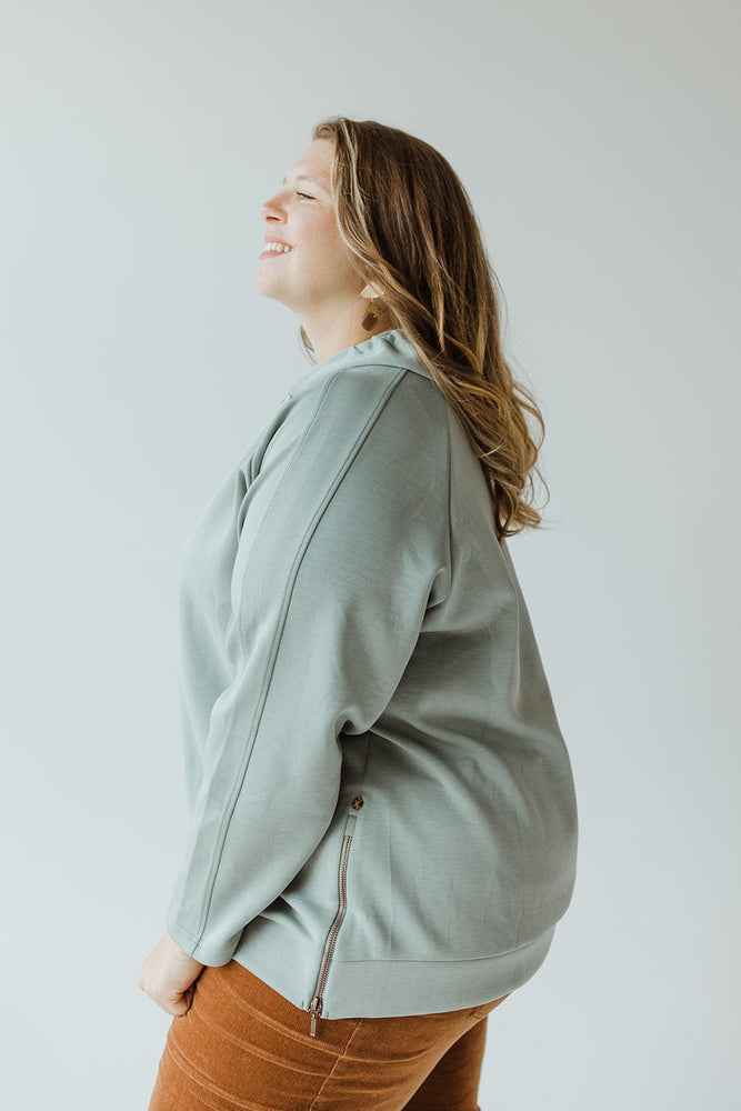 A person in the Yesta Light As Air Double-String Hoodie in Quietude, unzipping the side zipper near the hem, exudes luxurious comfort.