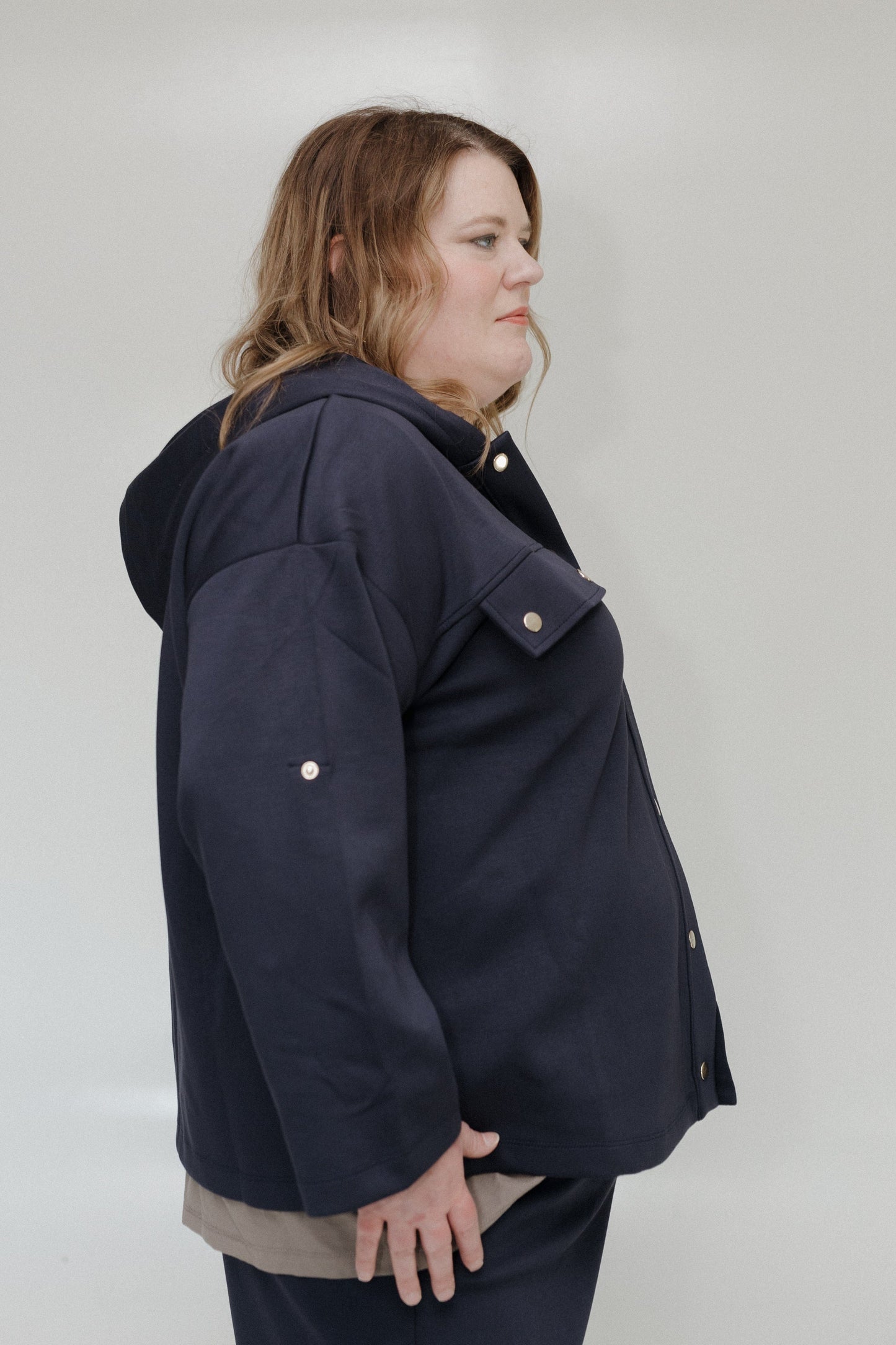 Person wearing a navy blue jacket with a hood on a plain background