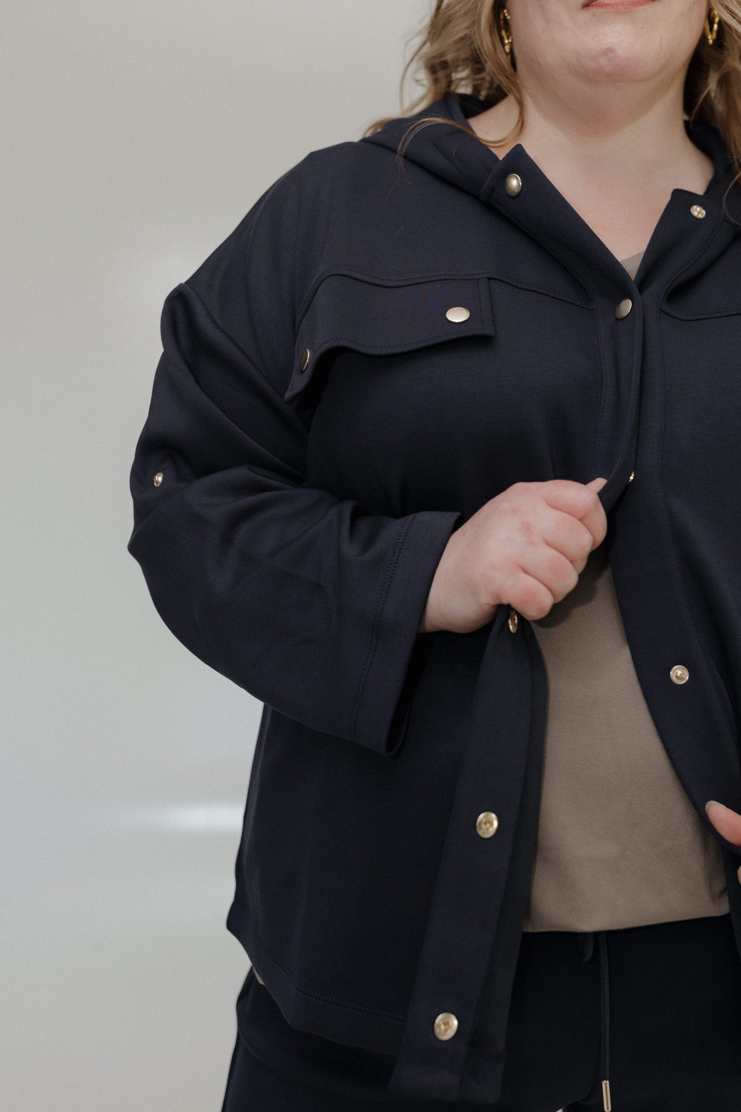 Person wearing a dark blue jacket with gold buttons against a neutral background