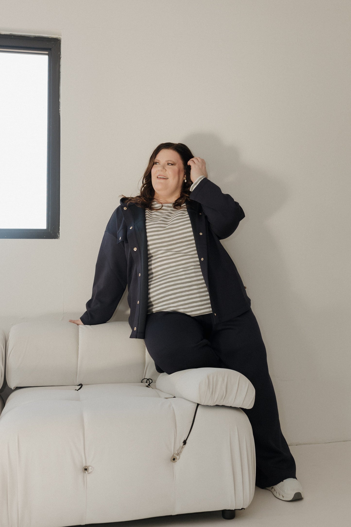 Person sitting on a white couch in a minimalistic room.