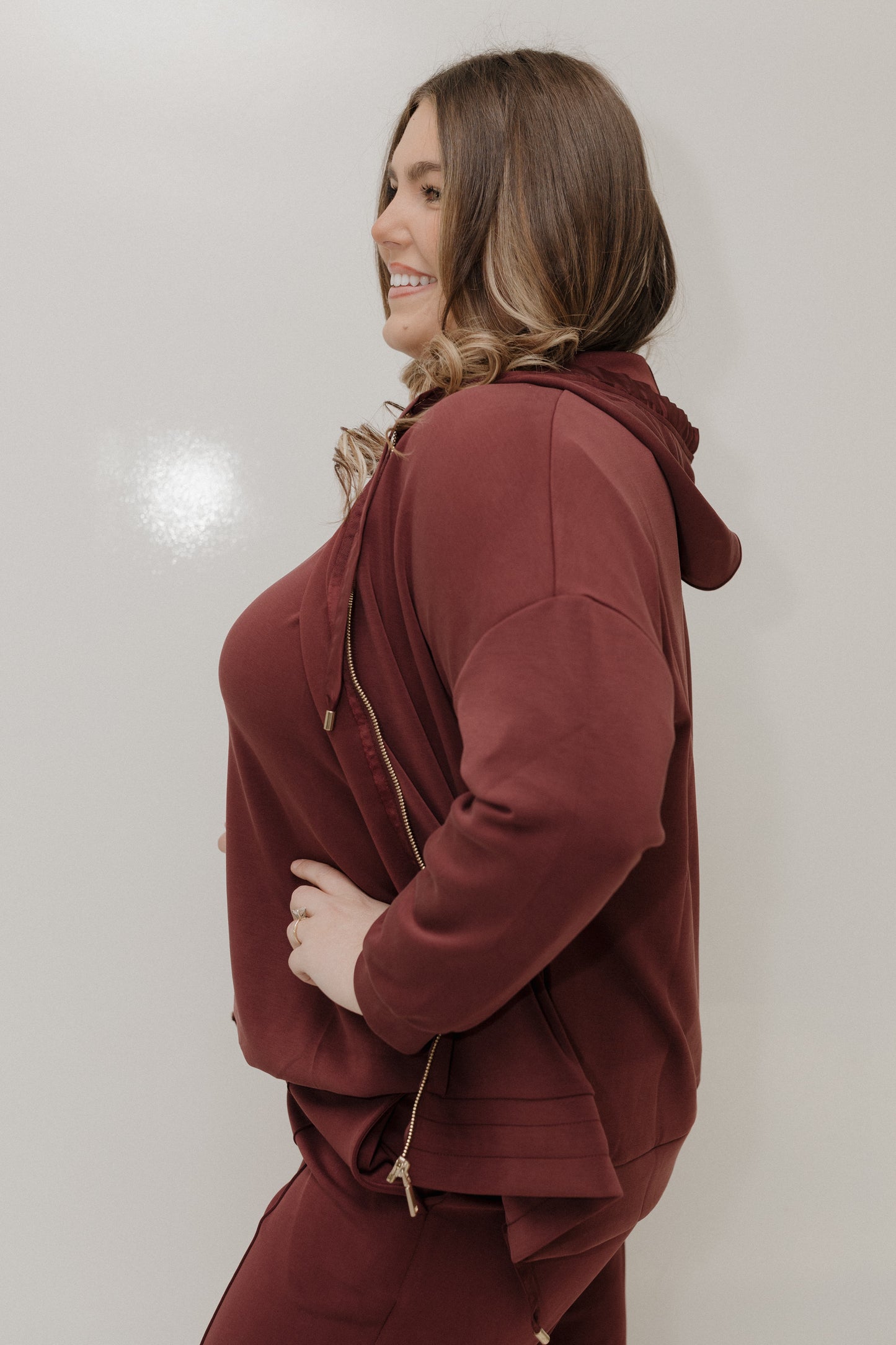 Woman wearing a maroon tracksuit against a plain background