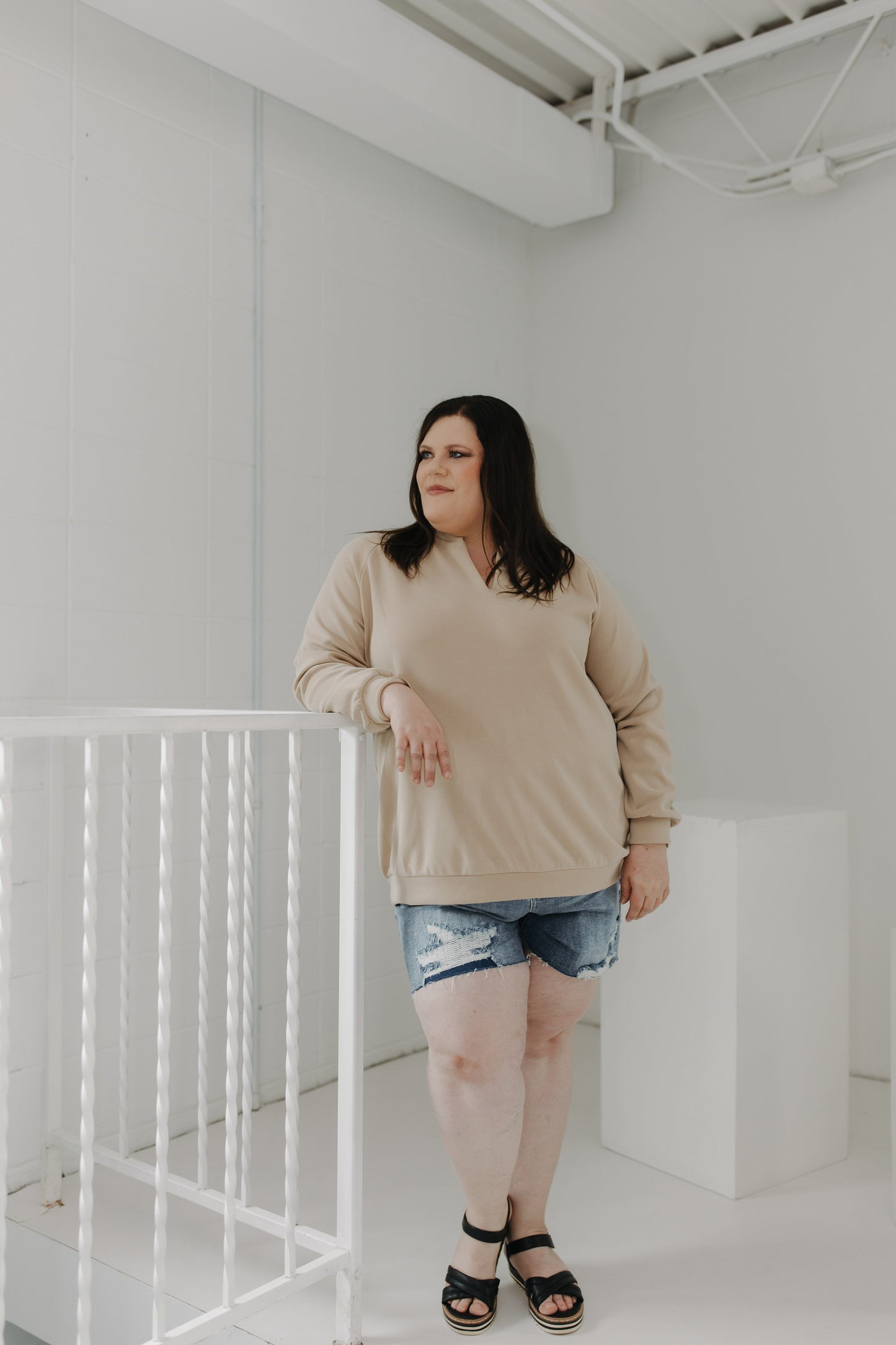 Woman standing in a minimalistic room with white walls and a white railing.
