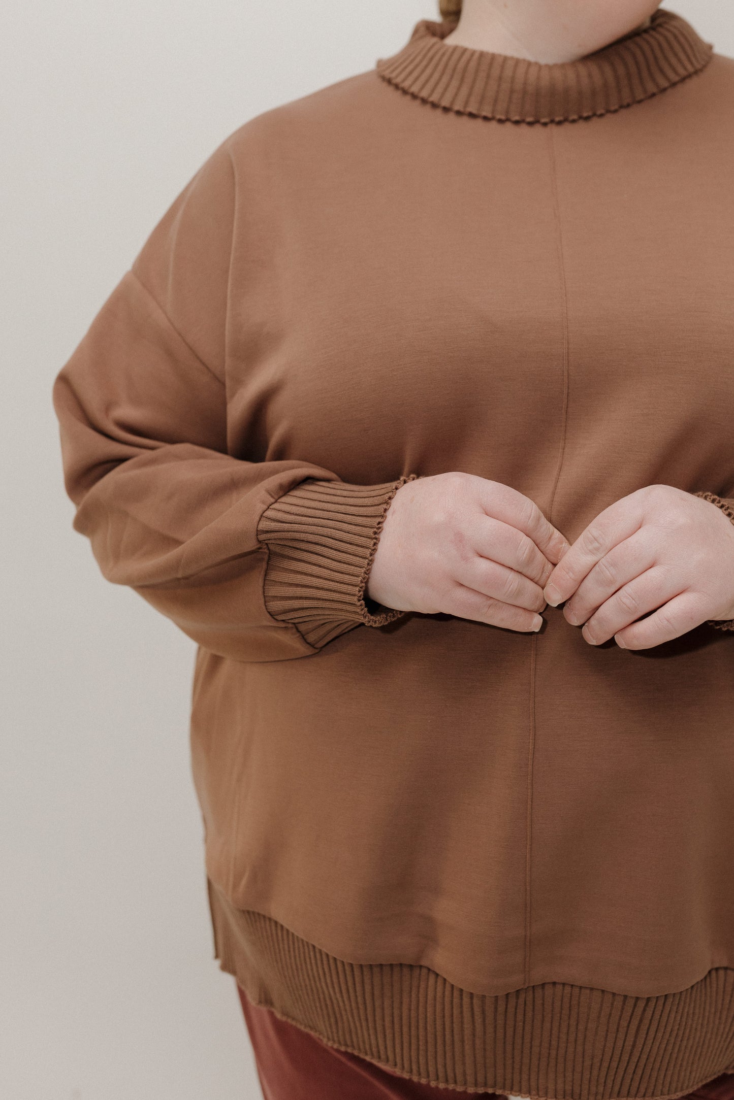 Brown sweater worn by a person on a plain background