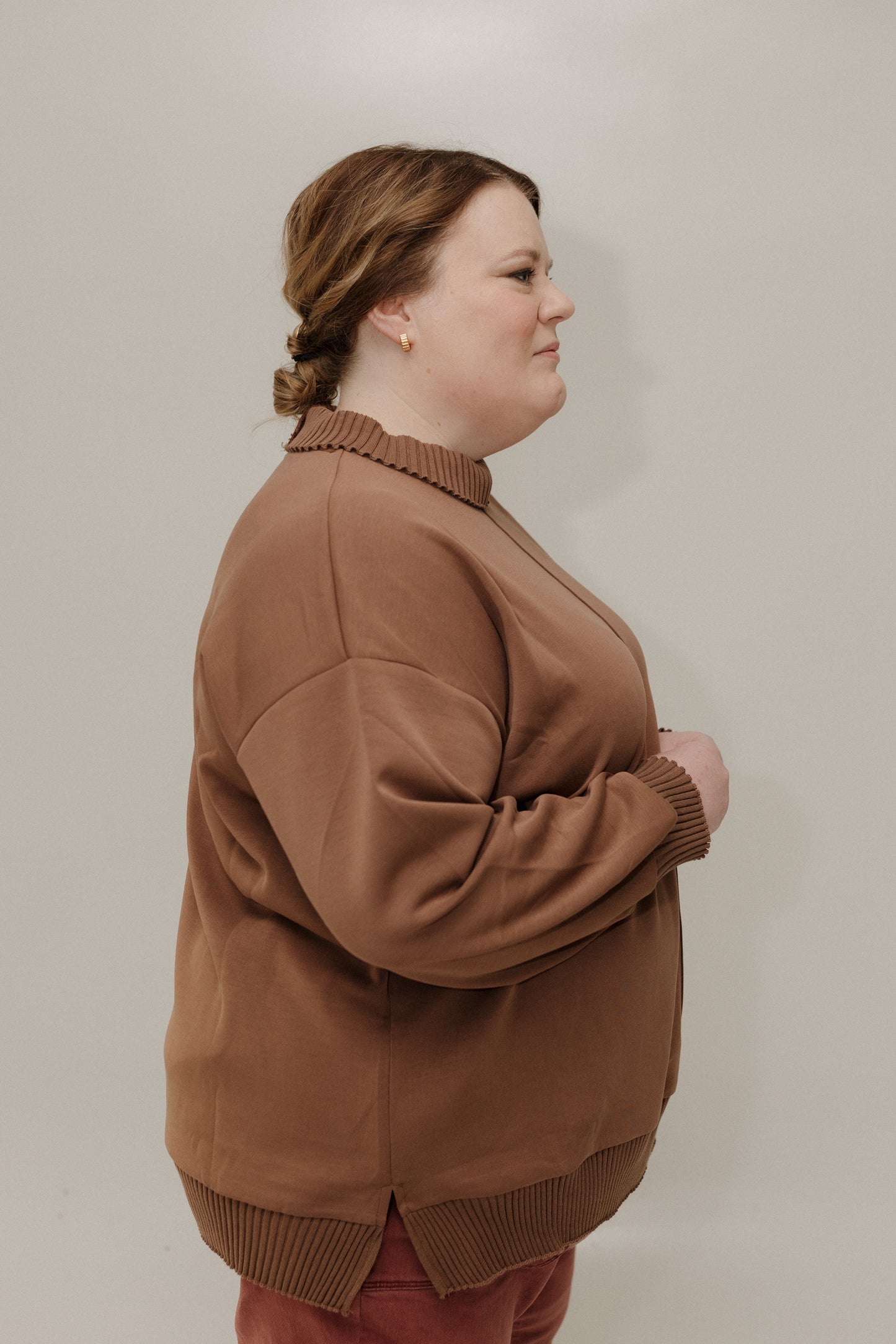 Woman wearing a brown sweater against a plain background