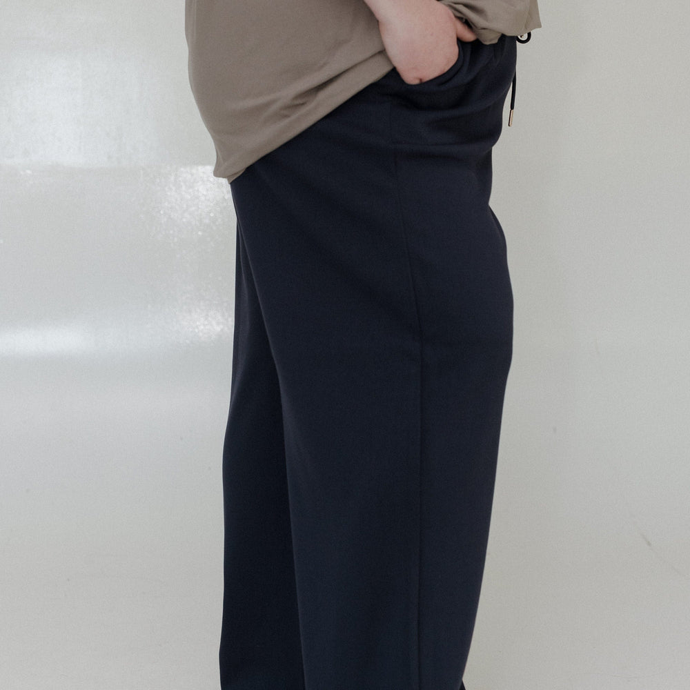 Person wearing a beige top and black wide-leg pants on a white background