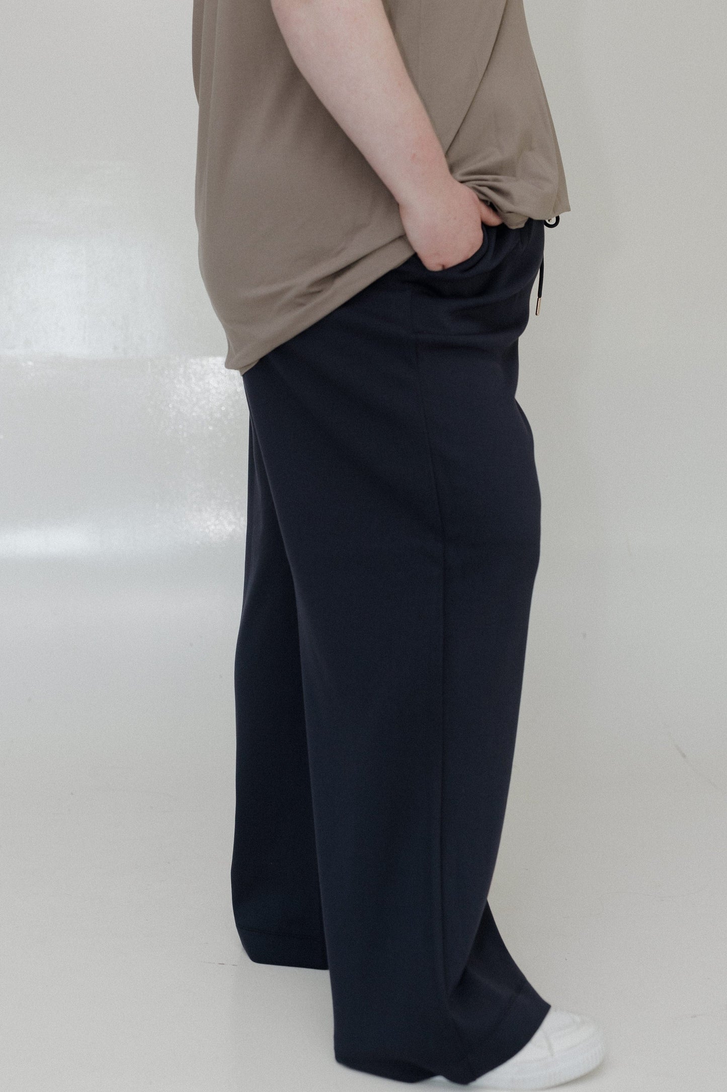 Person wearing a beige top and black wide-leg pants on a white background