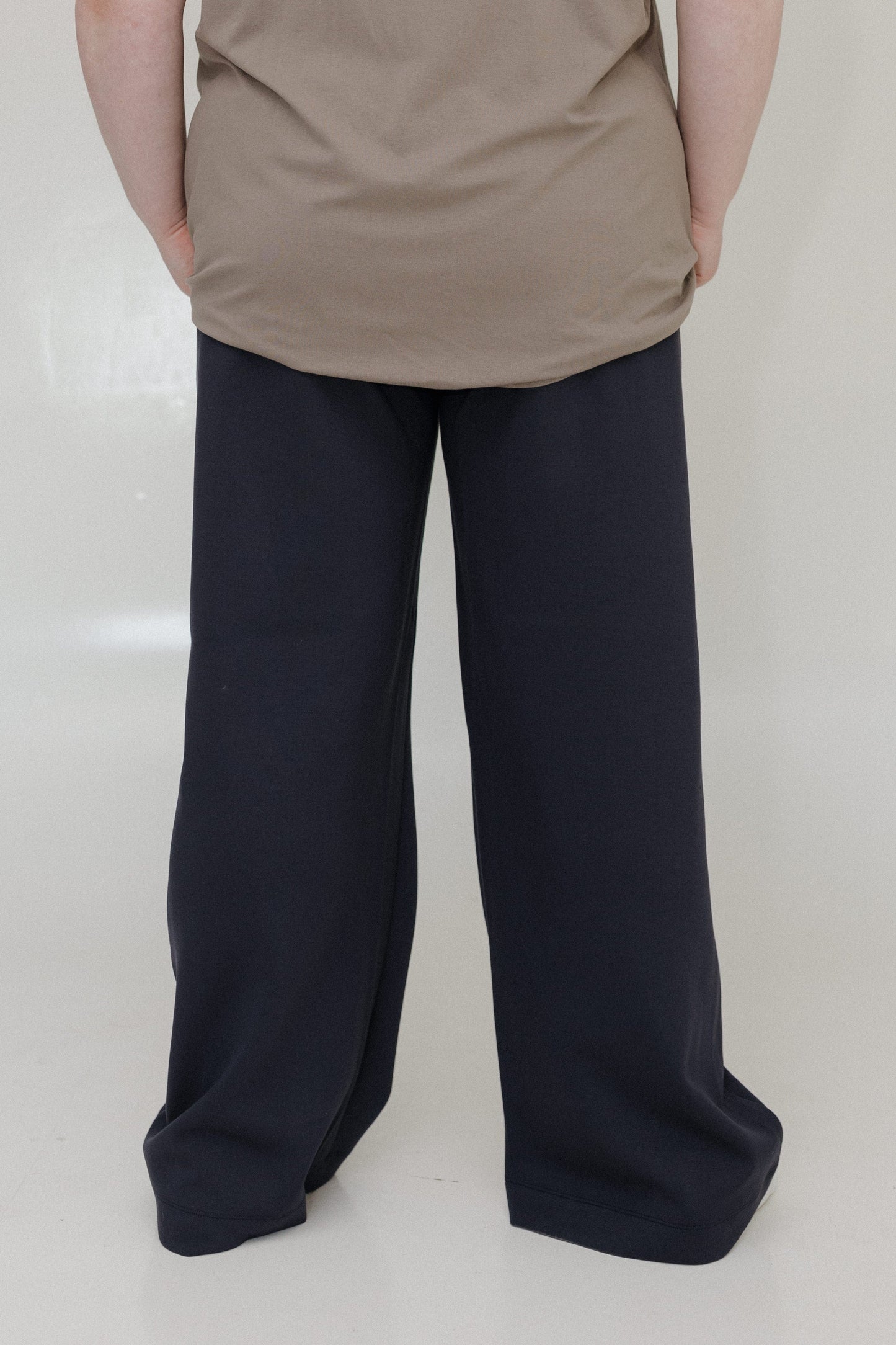 Person wearing a beige top and black wide-leg pants on a white background