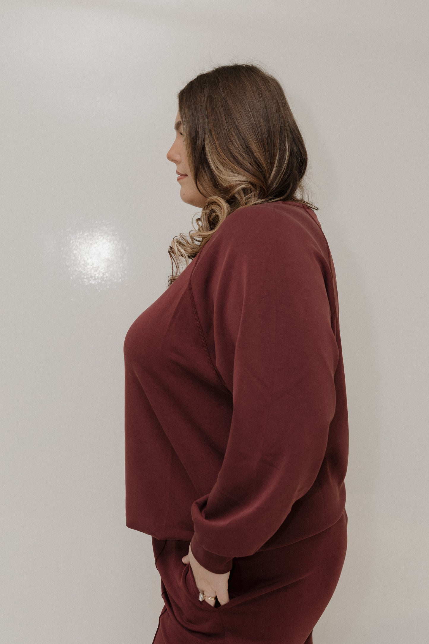 Woman wearing a maroon outfit against a plain background
