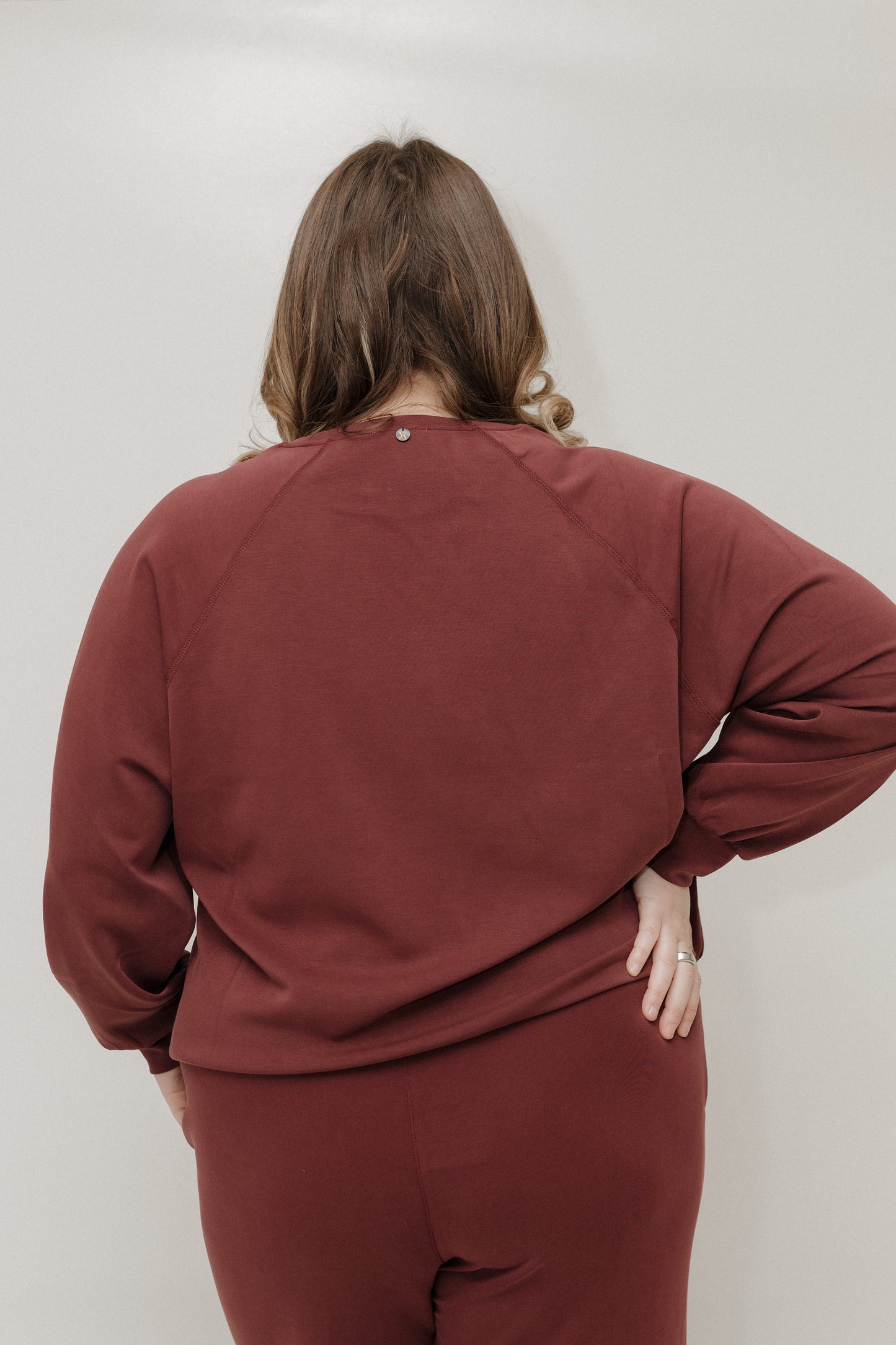 Person wearing a maroon tracksuit against a plain background