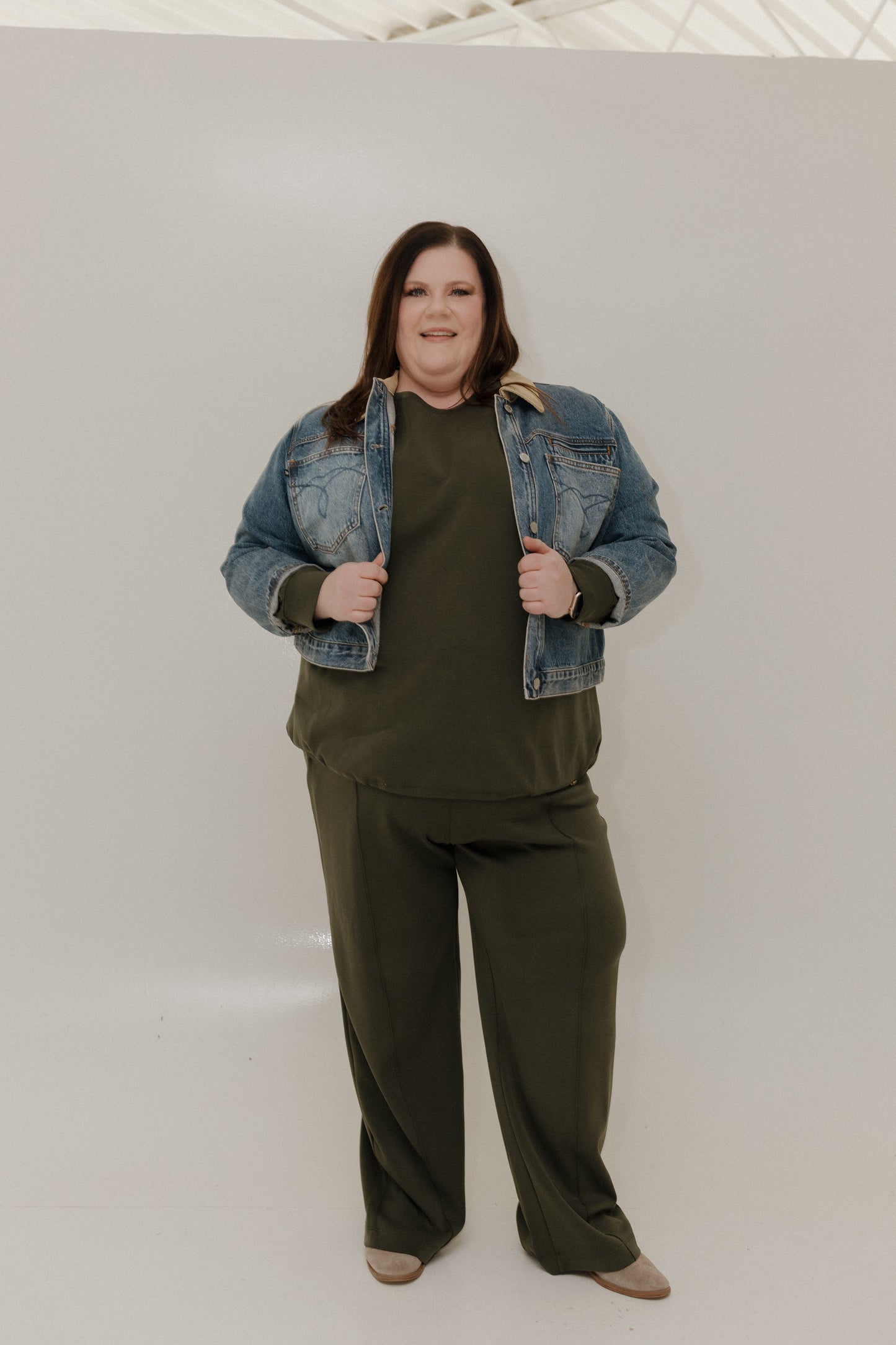 Person wearing a green outfit with a denim jacket on a white background
