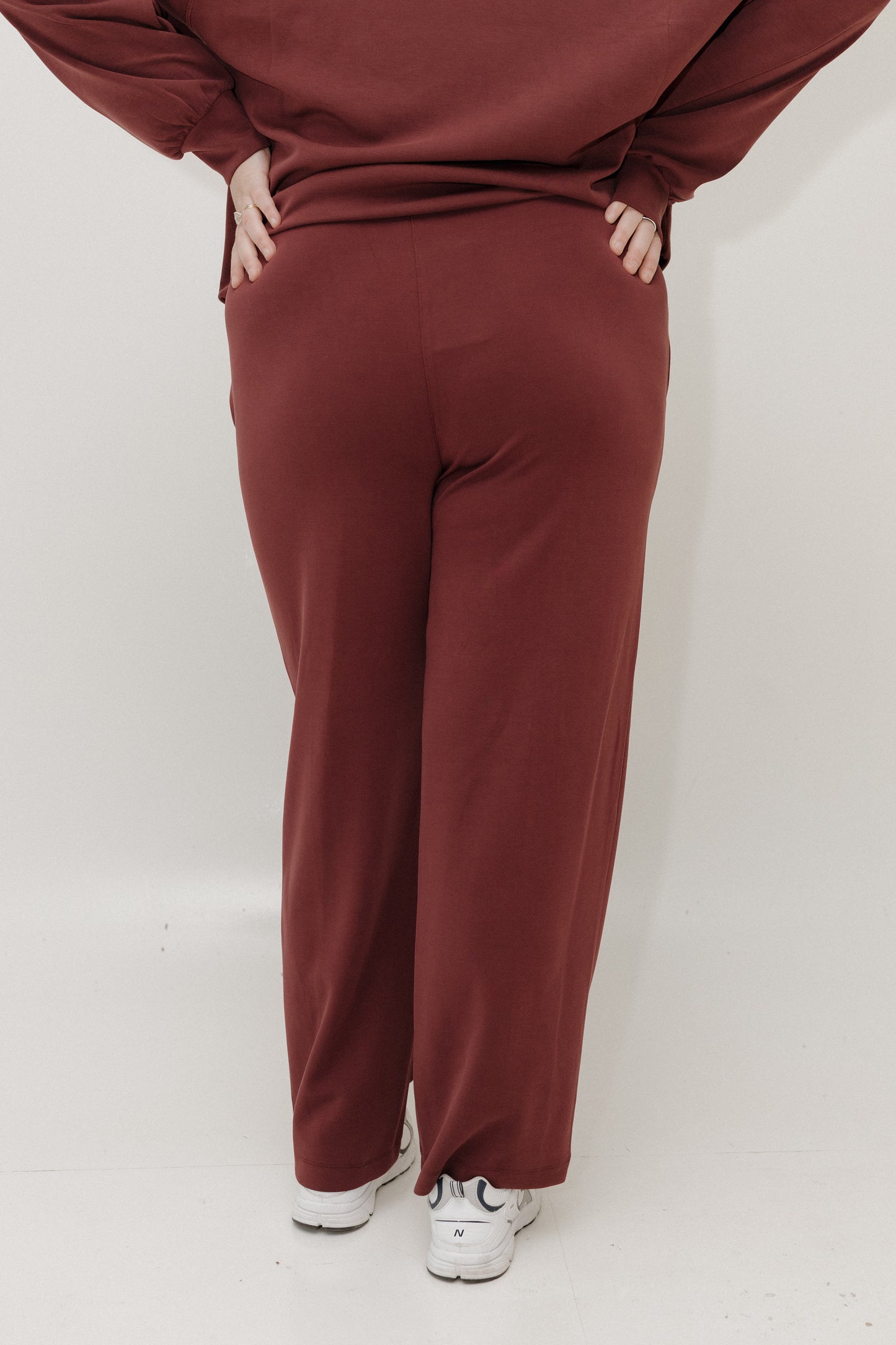 Maroon tracksuit worn by a person on a white background