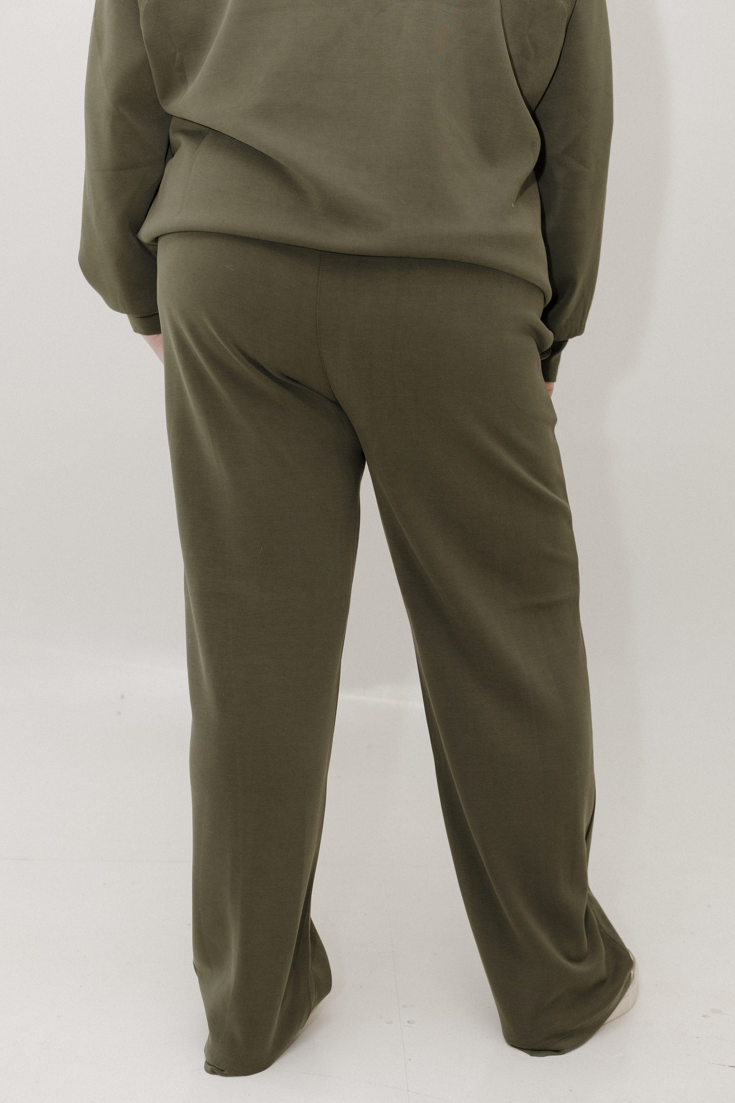 Person wearing olive green sweatshirt and pants on a white background