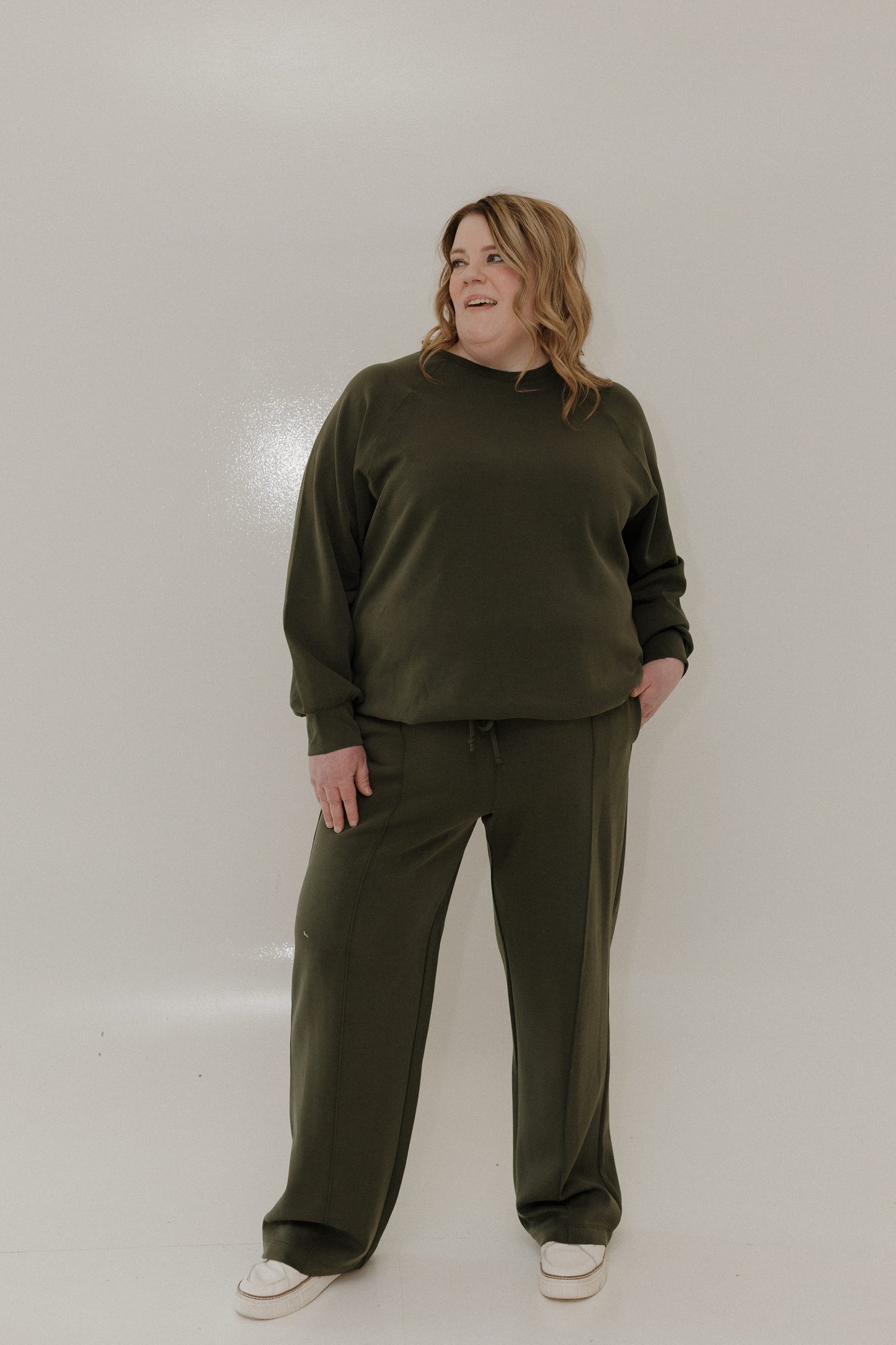 Person wearing an olive green outfit against a white background