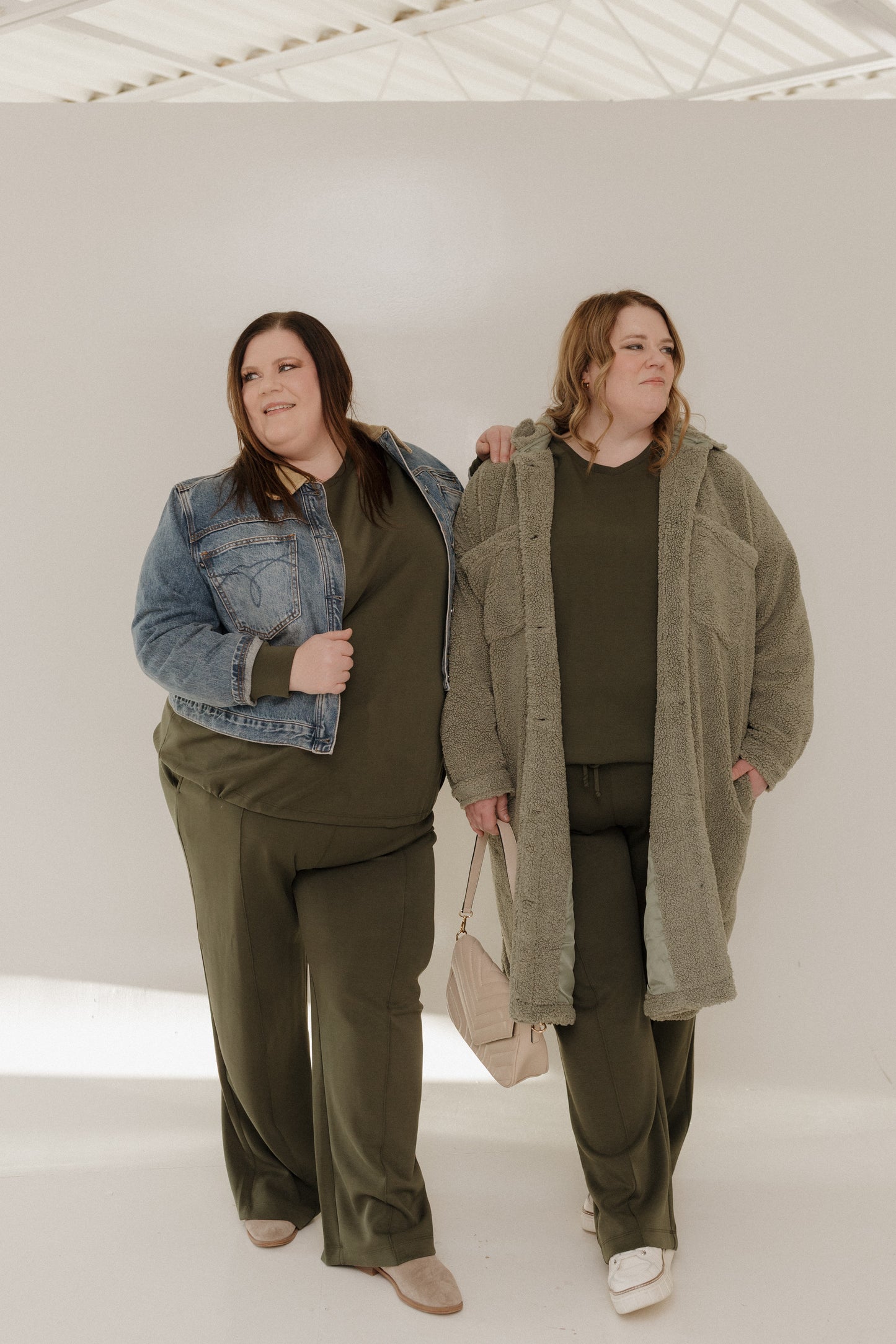 Two women wearing green outfits with a white background